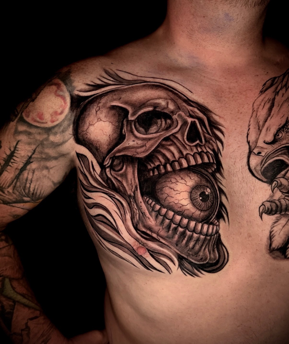 Black and grey skull and eyeball chest tattoo